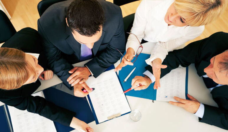 Personen sitzen am Tisch und besprechen sich.