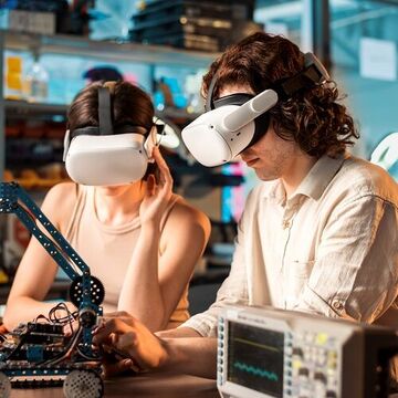 Junge Männer und Frauen mit VR-Brillen machen Experimente zur Robotik in einem Labor.