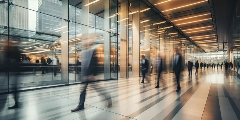 Langzeitbelichtung einer Gruppe von Geschäftsleuten, die durch eine helle Büro-Lobby gehen 