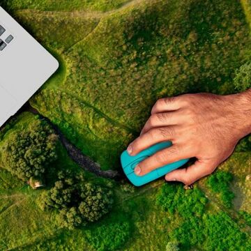 Hand an einer Maus für einen Landtop mit einem landschaftlichen Hintergrund