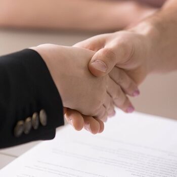 Mann und frau schütteln hände über einem vertrag