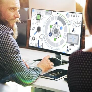 Zwei Personen sitzen vor einem Computer