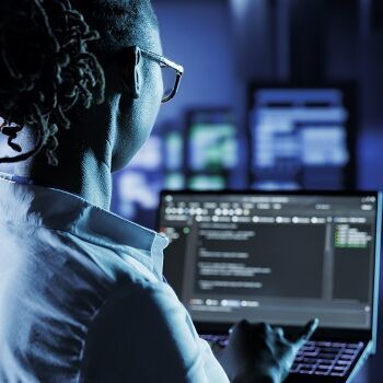 Frau mit Laptop in Hand vor vielen Servern 