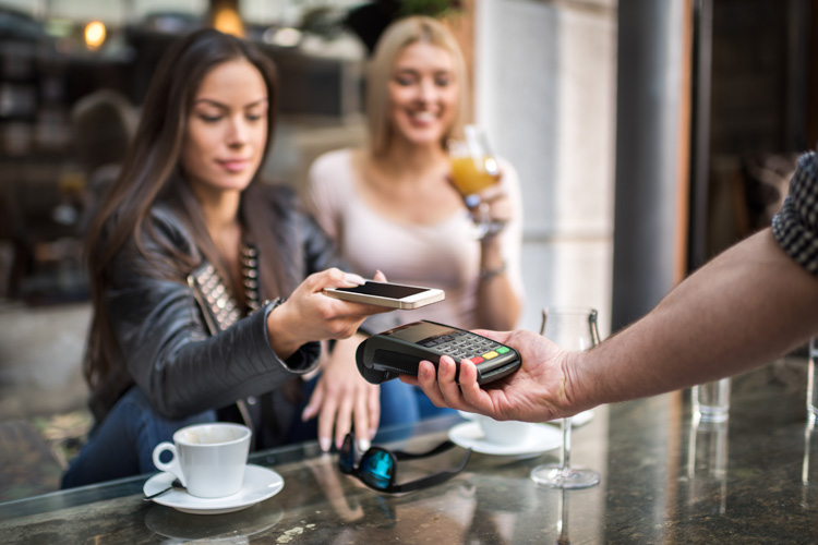 Zwei Damen zahlen Kaffee mit der Kreditkarte.