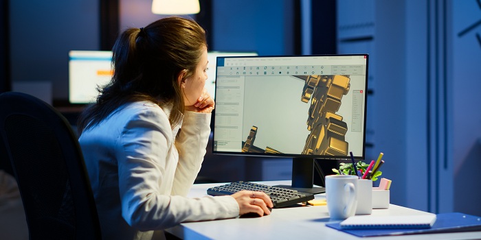 Müde Architektin, die an modernen CAD-Programmüberstunden arbeitet und am Schreibtisch im Start-up-Büro sitzt. Industrieingenieurin studiert Prototypidee auf dem PC, die CAD-Software auf dem Gerätedisplay zeigt