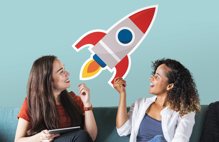 Zwei Frauen halten einen Icon einer Rakete die Start Up Gründungen symbolisieren soll