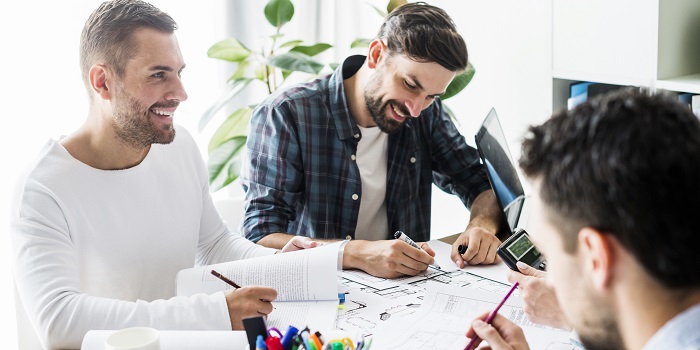 gruppe lachender Geschäftsmänner am tisch sitzend und am arbeiten 