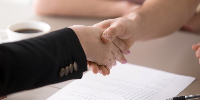 Mann und frau schütteln hände über einem vertrag