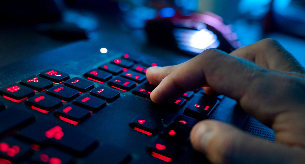 Person tippt auf eine rot leuchtende Tastatur