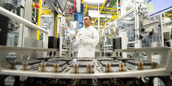 Mann in weißen Schutzanzug in einer Produktionshalle mit modernen Fertigungsgeräten 