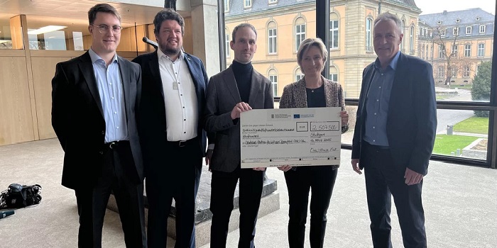 4 Personen stehen hinter einem Scheck für 2507500€ 